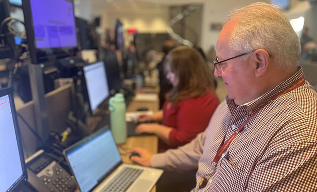 A group of Alabama Emergency Management Agency (AEMA) employees at a computer